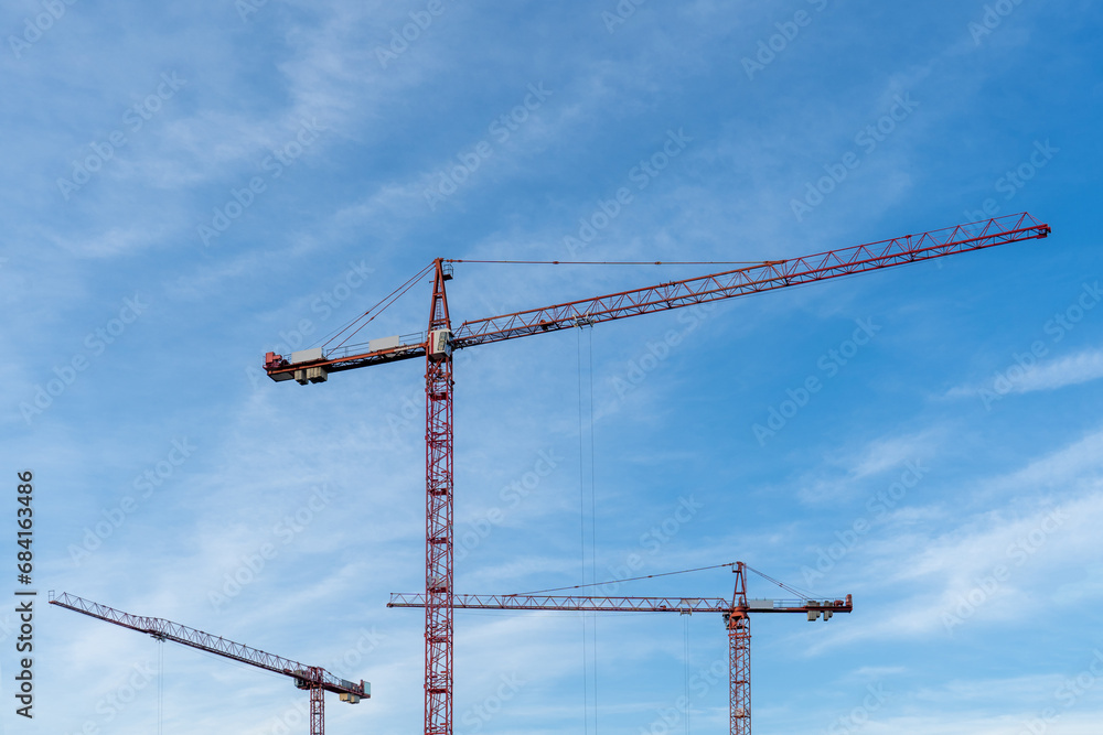 Construction cranes on blue cloudy sky background Construction cranes on blue cloudy sky background