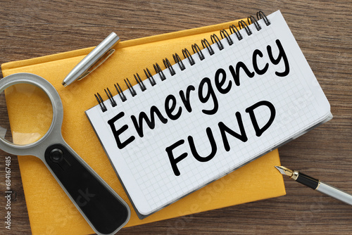 EMERGENCY FUND yellow notepad with text on the page. white pen