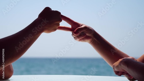Rock paper scissors being played by two young woman. Close up view female hands playing stone, scissors and paper on sea background, funny carefree game. Friendship, dealing with conflict, having fun. photo