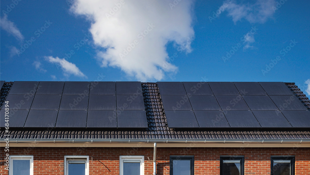 Fototapeta premium Newly built houses with solar panels attached on the roof Close up of new building with black solar panels. 