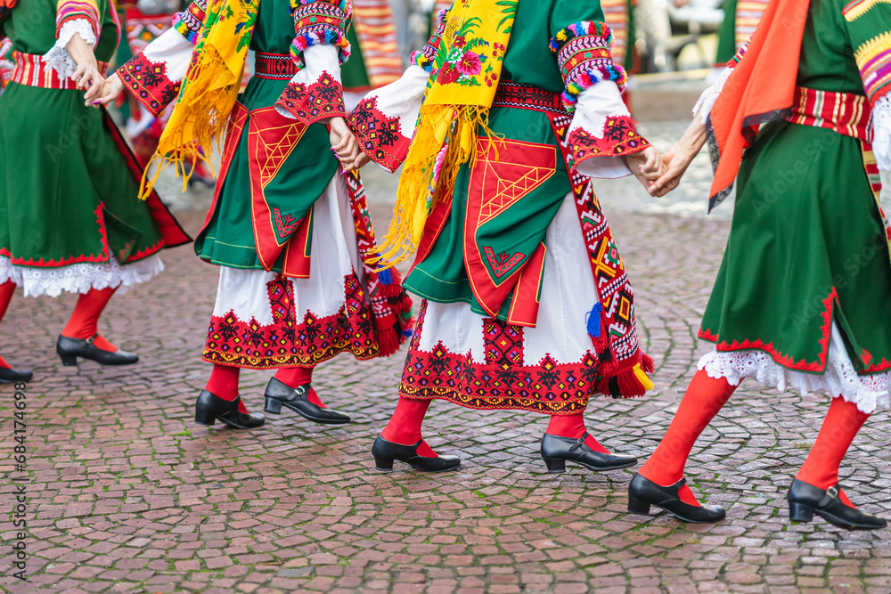 Girls in traditional Bulgarian costumes dancing folk dance holding hands