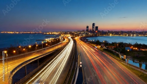 the motion blur of a busy urban highway during the evening rush hour the city skyline serves as the background illuminated by a sea of headlights and taillights