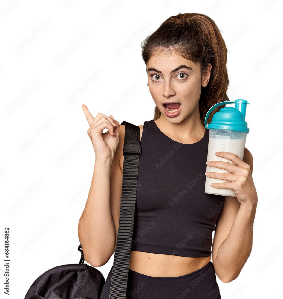 Athletic Caucasian woman holding protein shake pointing to the side Athletic Caucasian woman holding protein shake pointing to the side