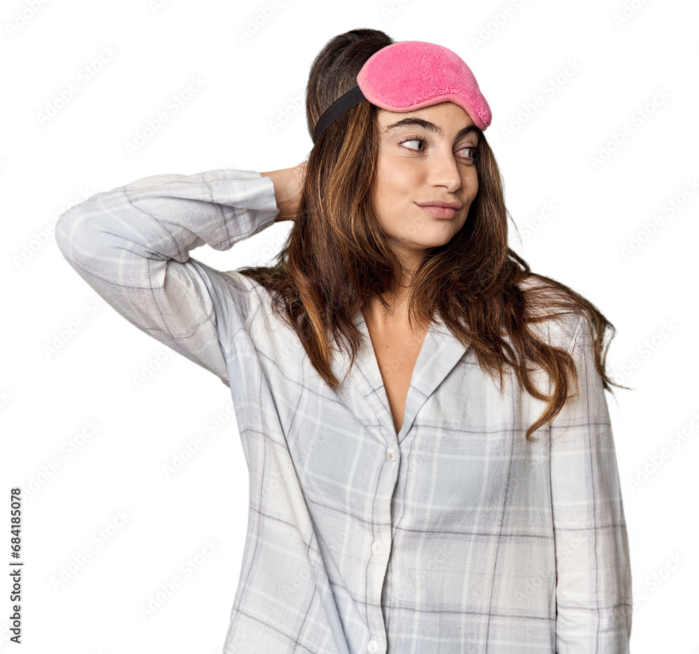 Young Caucasian woman in pajamas with mask touching back of head, thinking and making a choice. Young Caucasian woman in pajamas with mask touching back of head, thinking and making a choice.