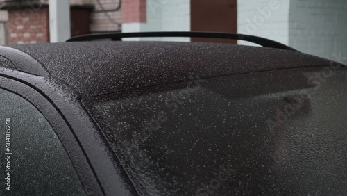 Wet snow and frost cause the car body and windshield to become covered with a layer of ice and snow. The car freezes in a parking lot on the street in winter. photo