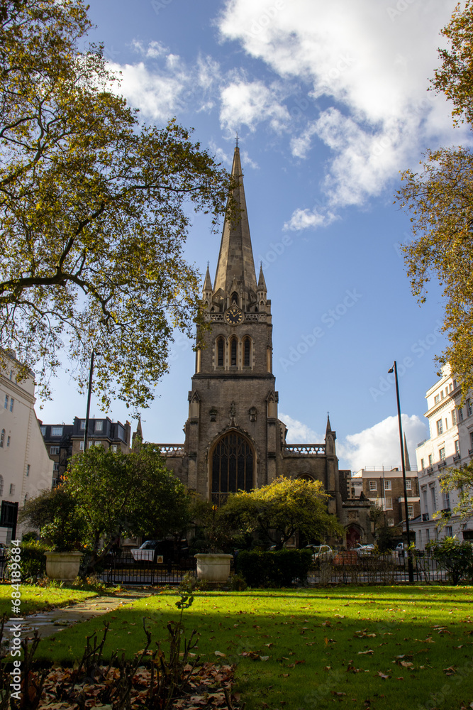 Gothic Church Spire Rising Above Autumn Foliage in a London Garden - A Captivating Urban Landscape