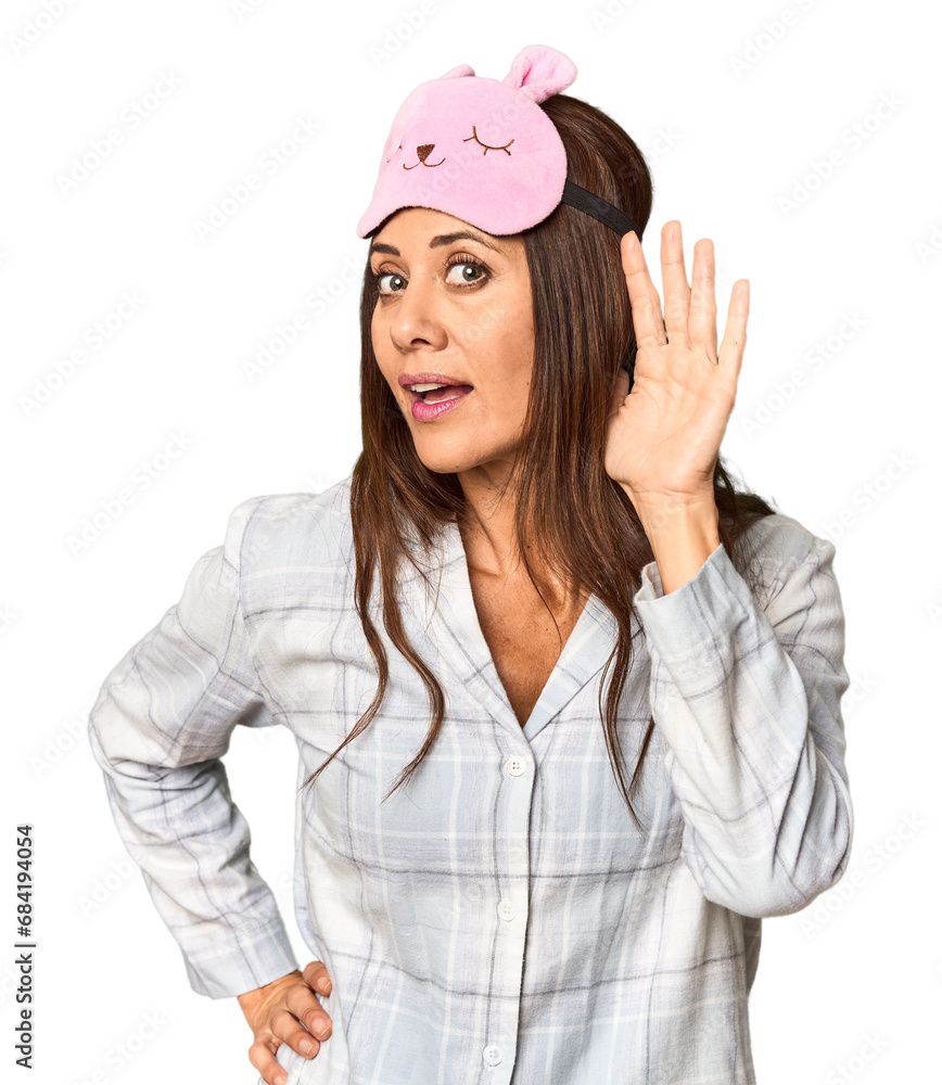 Middle-aged Caucasian woman in pajamas and mask in studio trying to listening a gossip. Middle-aged Caucasian woman in pajamas and mask in studio trying to listening a gossip.