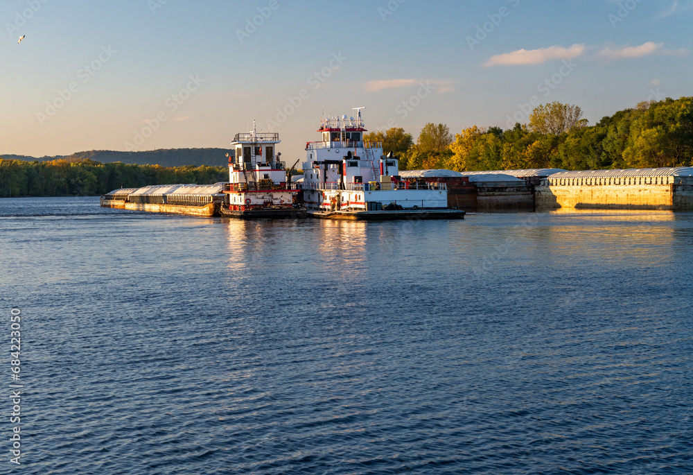 Fototapeta premium Large grain shipment on Upper Mississippi in barge being pushed by two large pusher tugs on river