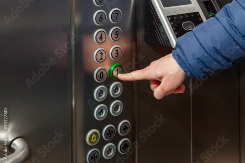 A man presses the floor button in the elevator of the business center photo