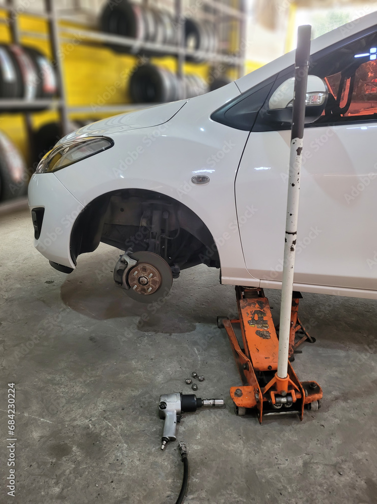 Car jack to lift the car for replace wheel and repair at garage, Tire replacement service, Fitting with balancing in the garage. Car jack to lift the car for replace wheel and repair at garage, Tire replacement service, Fitting with balancing in the garage.