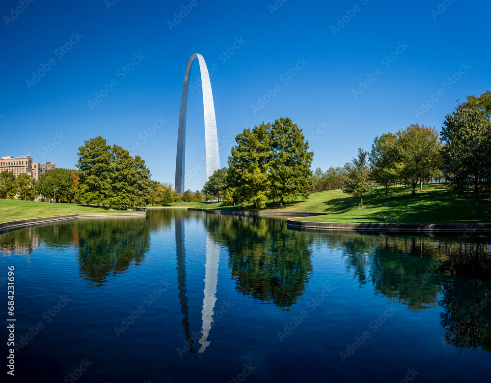 View across blue lake in the National Gateway Park to Gateway Arch in St Louis Missouri with reflection in the calm water - obrazy, fototapety, plakaty 