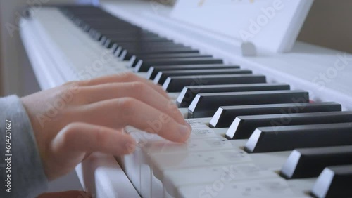 Close up child's hand playing piano at home. Little gir is learning piano. Camera view is parallel to keyboard.