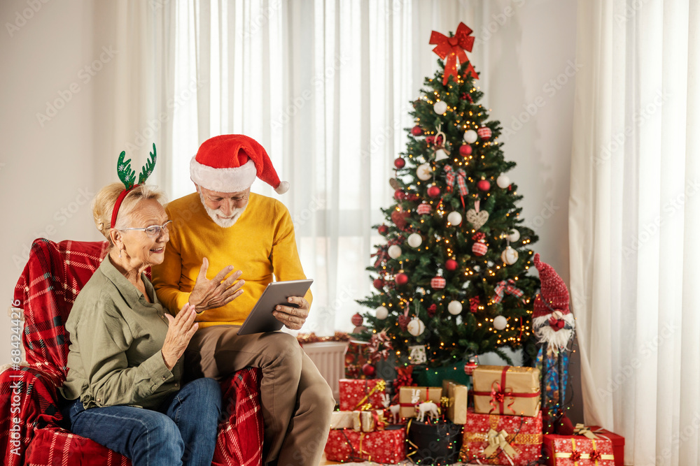 A senior couple is having a video call on tablet at home on christmas and new year. A senior couple is having a video call on tablet at home on christmas and new year.