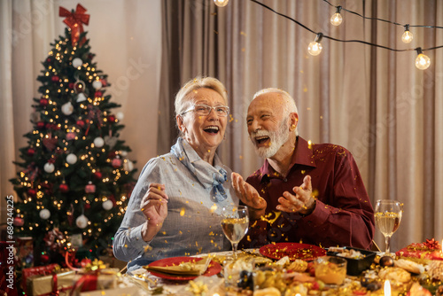 Photography A happy senior couple is celebrating Christmas and new year's eve at dining table at home with confetti
