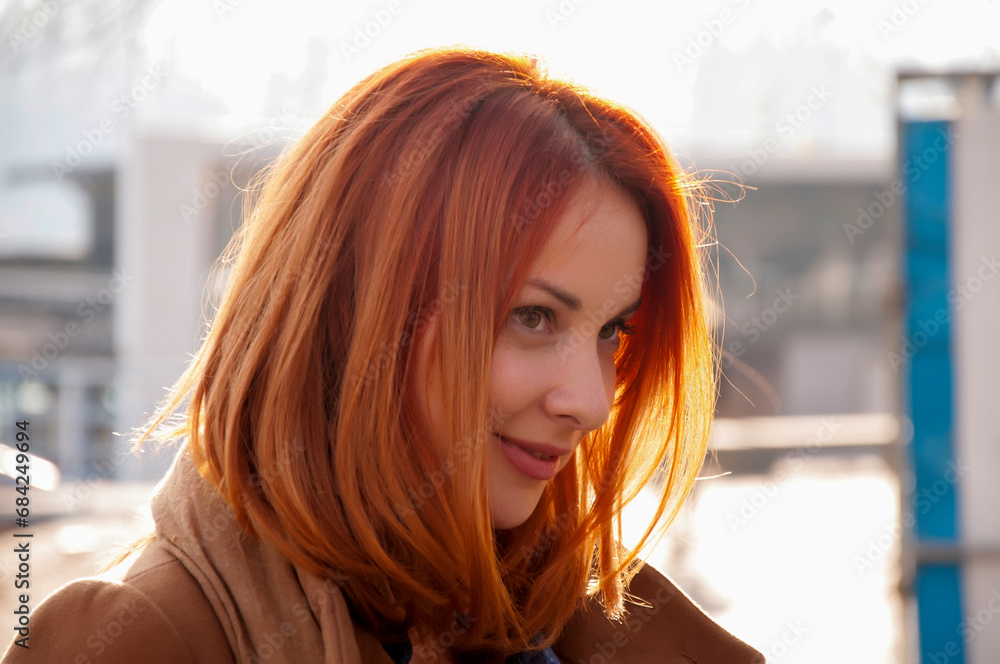 Autumn portrait of a young attractive long haired woman with red hair in the city. Beautiful redhead
