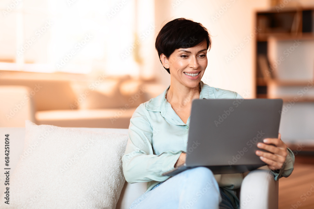 Woman comfortably working online from home via laptop indoor Woman comfortably working online from home via laptop indoor