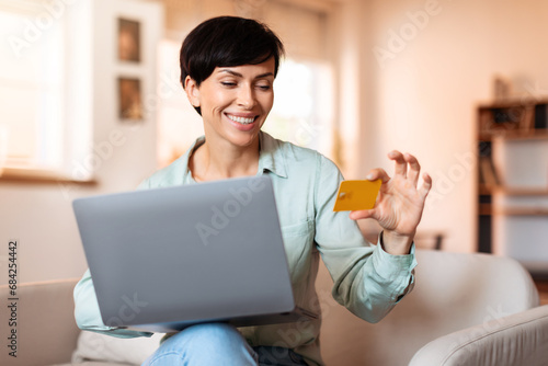 lady browsing online stores on laptop using credit card indoor