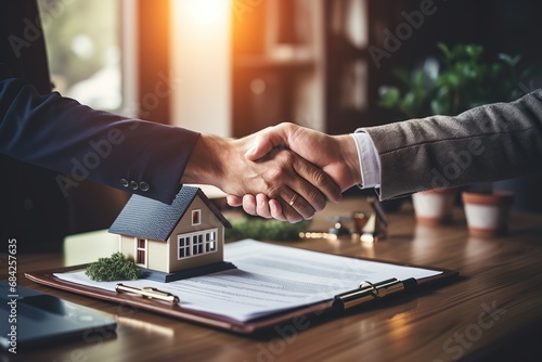 House model is displayed on wooden meeting table with in the blurred background of real estate agent and client discuss terms and conditions of house loan or rental lease contract. Entity photo