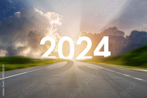 Go to the New Year 2024. Happy New Year greeting card 2024, Happy New Year 2024 letters on the highway road in the destination of empty asphalt road with sunset or sunrise light above asphalt road.