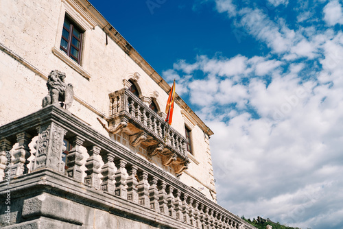 Flag on a flagpole hangs on a balcony with a stone carved balustrade of an ancient building