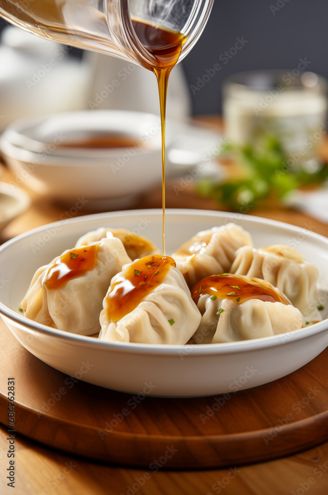 Pouring sauce in a bowl with dumplings. Vertical, side view.
