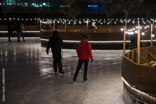 Ice rink in winter. People skate in the park in the evening. Skates are skating on ice