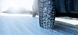 Car is on a snow-covered winter road. Сlose up of winter tire.