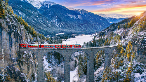 Aerial view of Train passing through famous mountain in Filisur, Switzerland. Landwasser Viaduct world heritage with train express in Swiss Alps snow winter scenery. photo