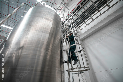The male worker down the ladder is for inspection stainless steel tank chemical. photo
