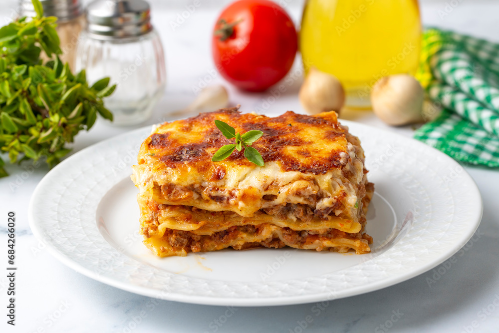 Portion of ground beef lasagna topped with melted cheese and garnished with fresh parsley served on a plate in close view for a menu