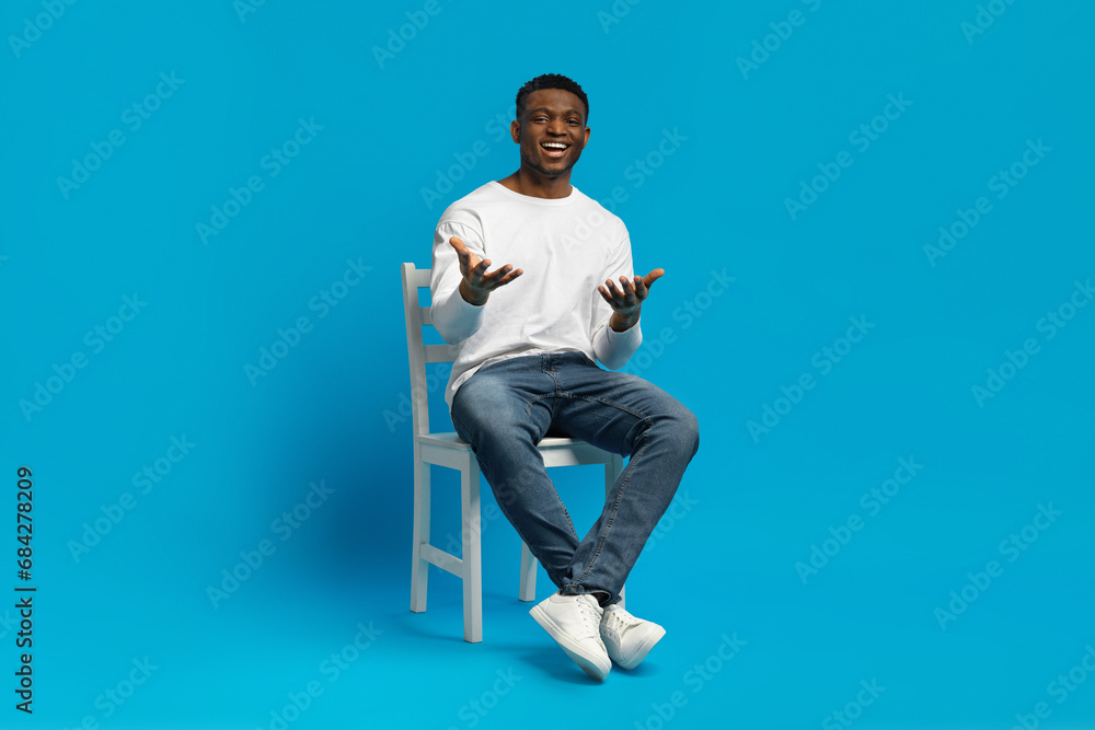Confident handsome black guy sitting on chair, gesturing Confident handsome black guy sitting on chair, gesturing