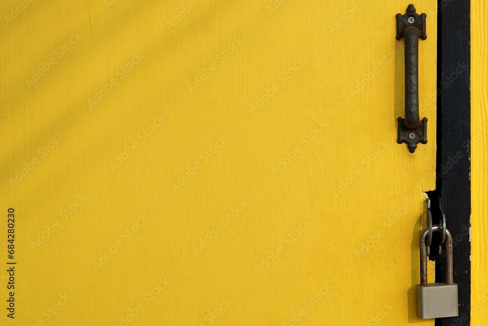 A wooden yellow door with a padlock for background and texture, design small shop concepts. A wooden yellow door with a padlock for background and texture, design small shop concepts.