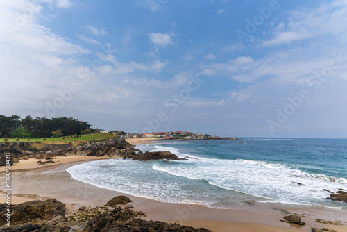 Playa de Portillo with Playa de Comillas in the background with the Cantabrian sea and a blue sky on top, Comillas, Cantabria, Spain photo