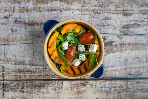 pumpkin salad with arugula and feta and tomato in a bowl