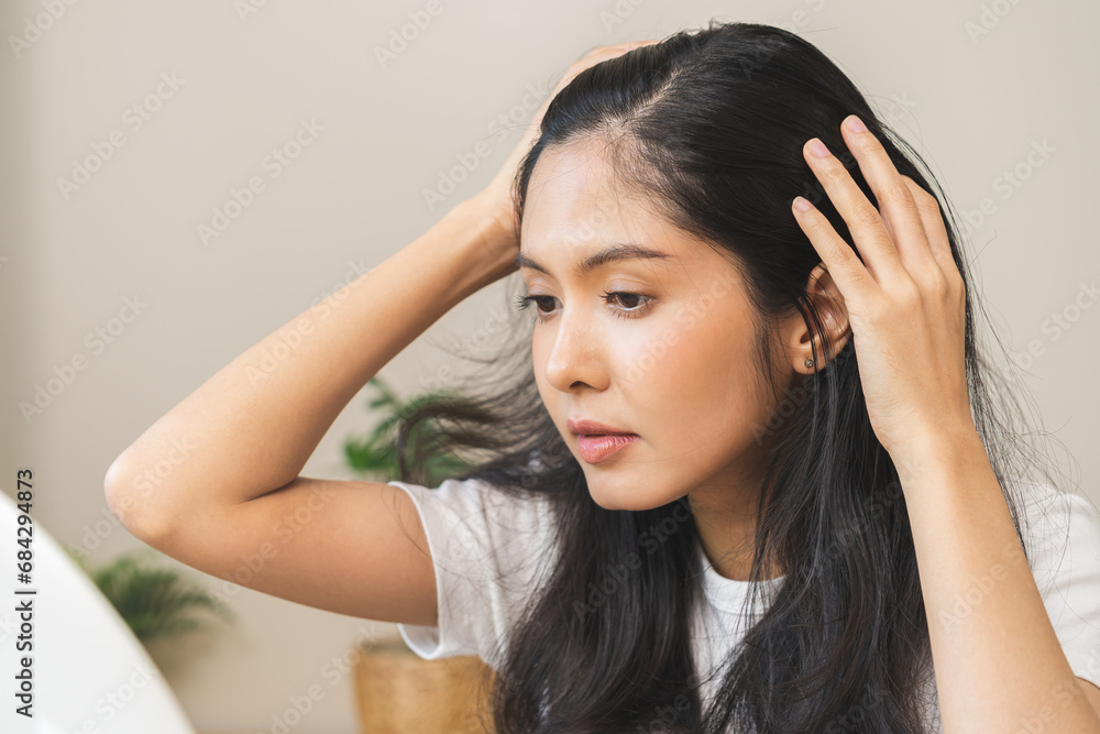 Damaged hair symptom, problem hair fall asian young woman, girl worry about balding, looking at scalp in mirror, hand in break into front hair loss, thin problem. Health care treatment for beauty. Damaged hair symptom, problem hair fall asian young woman, girl worry about balding, looking at scalp in mirror, hand in break into front hair loss, thin problem. Health care treatment for beauty.