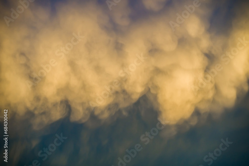 Unusual sunlit fluffy rainclouds in dark blue sky photo