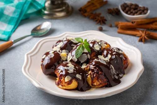 Delicious profiteroles with chocolate and white plate.