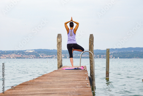 woman on a wooden pier on a lake doing a yoga pose photo