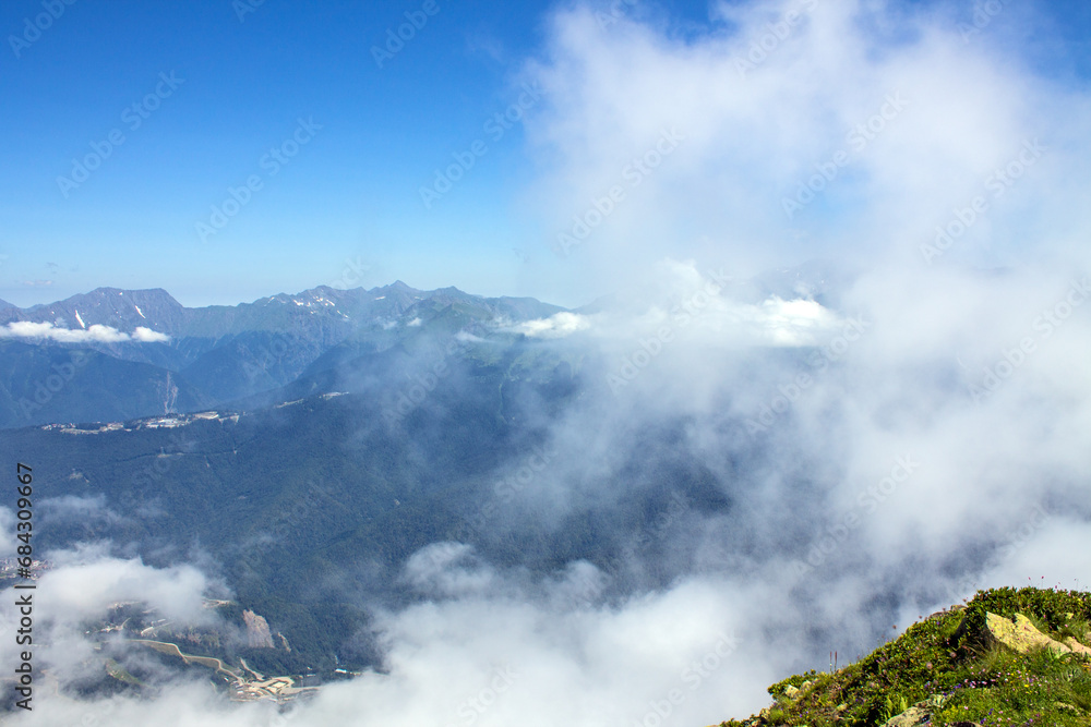 Dramatic landscape with mountain tops and white clouds against a blue sky background and space to copy