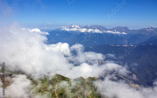 Dramatic landscape - white clouds among the peaks of the mountains against the blue sky on a sunny day and a space to copy