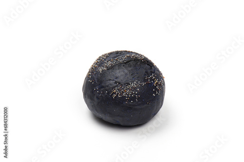 Close-up image of a smal burger bun naturally colored with activated charcoal sprinkled with poppy seeds, isolated on white background