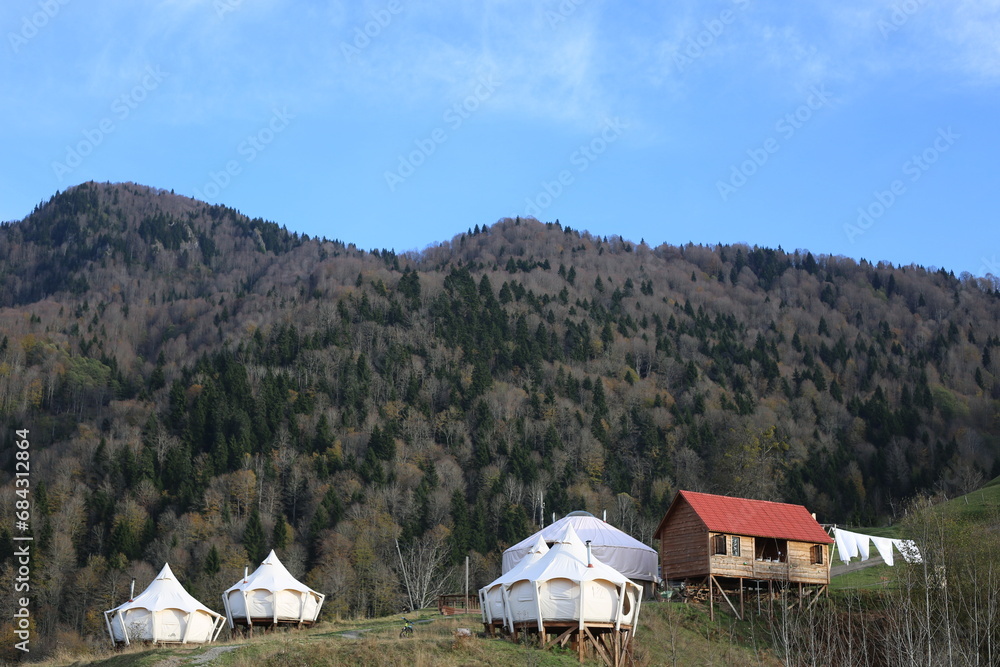 View of glamping tent on the nature in the beautiful countryside in the mountains in summer. White tent glamping camp. Luxury campsite.
