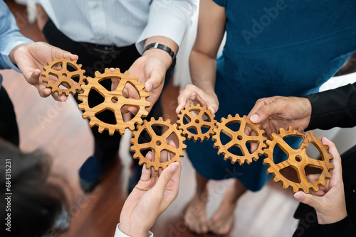 Office worker holding cog wheel as unity and teamwork in corporate workplace concept. Diverse colleague business people showing symbol of visionary system and mechanism for business success. Concord photo
