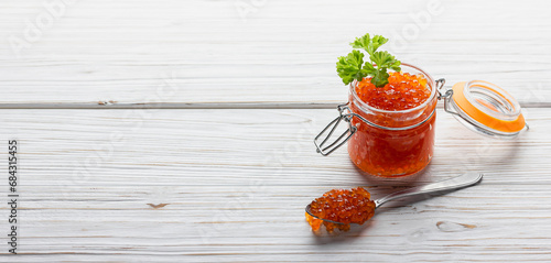 Red caviar in jar with fresh parsley