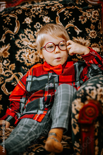 Little boy with glasses, sitting in an elegant chair