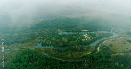 Green countryside. Drone valley. Trees crowns and river in misty clouds early morning beautiful foggy nature landscape top view.