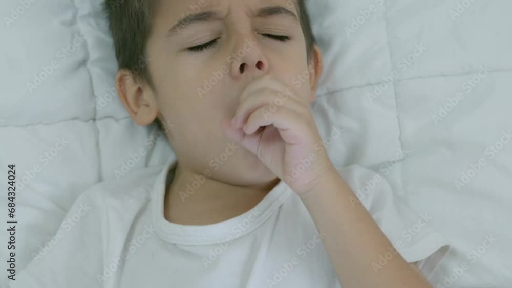 Caucasian boy child in the bed feeling unwell and angry , coughing as symptom for cold or bronchitis. Healthcare concept. Slow motion. High quality 4k footage Caucasian boy child in the bed feeling unwell and angry , coughing as symptom for cold or bronchitis. Healthcare concept. Slow motion. High quality 4k footage