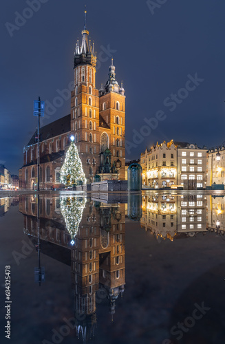 Krakow, Poland, St Mary's church and christmas tree on the Main Market Square reflecting in water