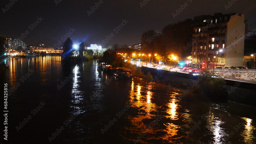 Promenade au bord de la Seine, pendant une soirée nocturne, réflexion lampadaire jaune et orange sur l'eau, animation et circulation urbaine, calme, froid et tranquille, hiver Paris, soirée agitée, 