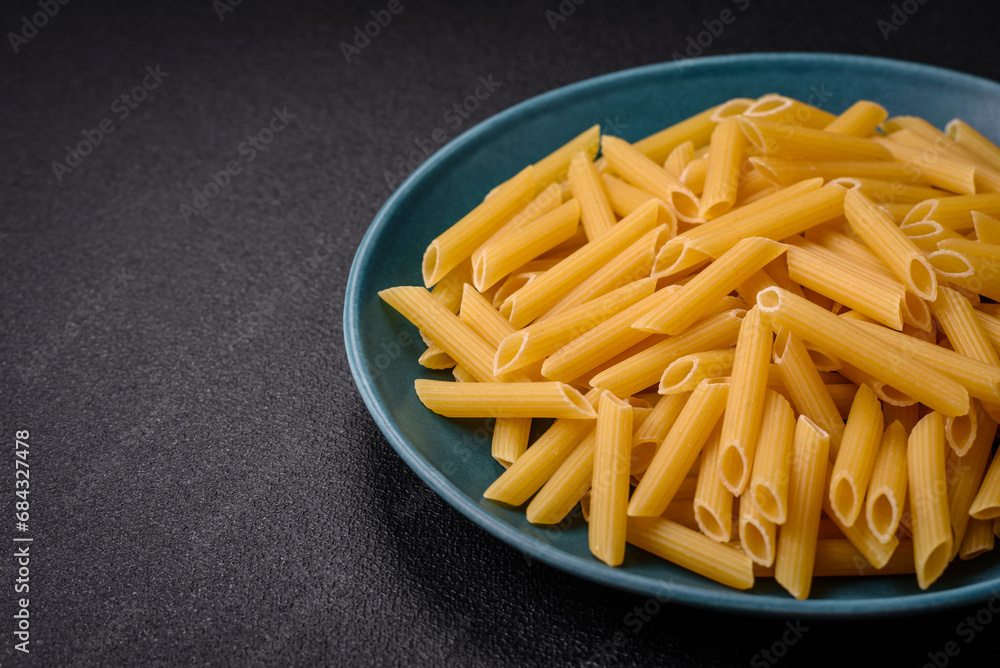 Raw penne pasta from whole grain wheat varieties with salt and spices Raw penne pasta from whole grain wheat varieties with salt and spices
